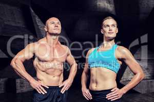 Composite image of muscular man and woman with hand on hip
