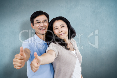 Composite image of couple standing together with thumbs up