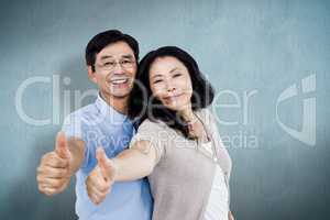 Composite image of couple standing together with thumbs up