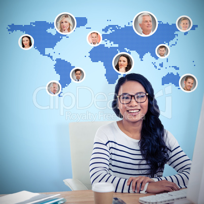 Composite image of smiling asian woman sitting at desk posing fo