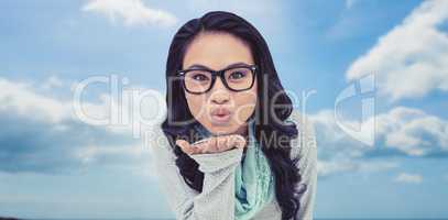 Composite image of asian woman blowing kiss to the camera