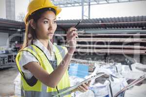 Composite image of architect woman with yellow helmet and plans