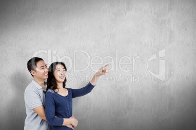 Composite image of happy couple with woman pointing up