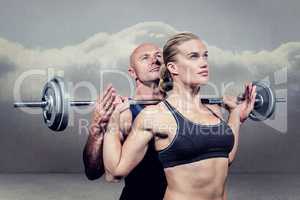 Composite image of trainer helping woman for lifting crossfit