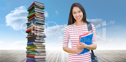 Composite image of college girl holding books with blurred stude