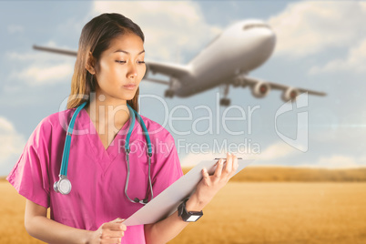 Composite image of asian nurse with stethoscope looking at the c