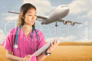 Composite image of asian nurse with stethoscope looking at the c