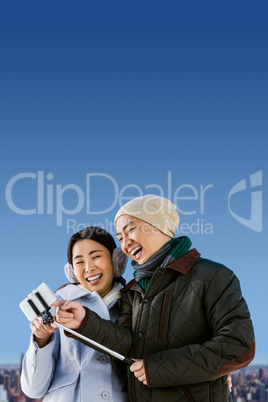 Composite image of couple laughing at their pictures taken on sm