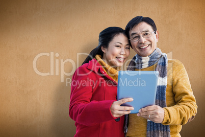 Composite image of asian couple on balcony using tablet