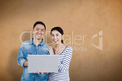 Composite image of portrait of couple using laptop