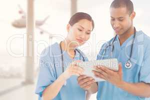 Composite image of surgeons looking at digital tablet in hospita