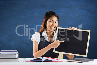 Composite image of smiling businesswoman pointing a blackboard