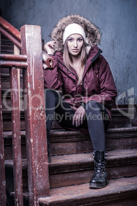Cute woman in winter coat on staircase