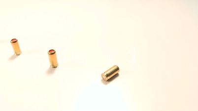 Line of pepper gas-cartridges and semi-automatic handgun, beauty-shot close-up on white background.