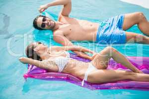 Couple smiling while relaxing on inflatable raft