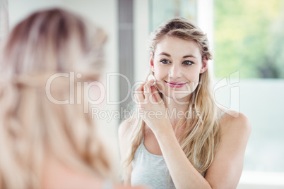 Smiling young woman applying blush