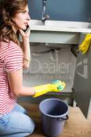 Woman using mobile phone while cleaning kitchen sink