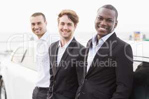 Well dressed men posing leaning on a limousine