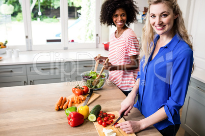 Happy female friends preparing food at home