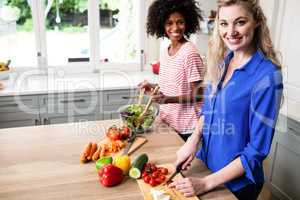 Happy female friends preparing food at home