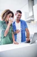 Couple using laptop while having a cup of coffee