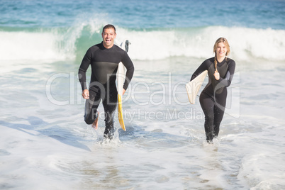 Couple with surfboard running on the beach