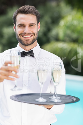 Happy waiter offering champagne