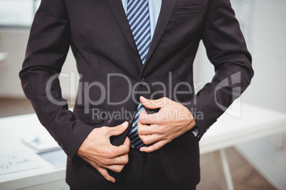 Businessman adjusting suit while standing in office