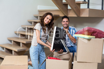 Portrait of happy couple unpacking computer from cardboard box