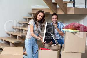 Portrait of happy couple unpacking computer from cardboard box
