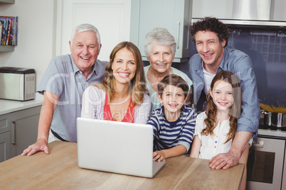Portrait of happy family using laptop in kitchen
