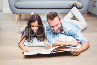 Father and daughter looking in picture book on floor