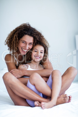 Portrait of mother and daughter embracing on bed