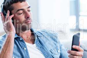 Young man listening to music while using mobile phone