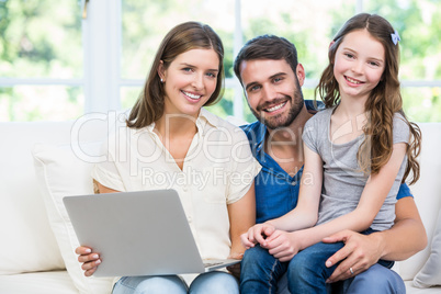 Portrait of family with laptop sitting on sofa