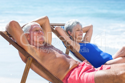 Cute mature couple lying on deckchairs