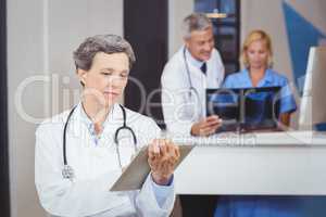 Female doctor using digital tablet with colleague checking X-ray