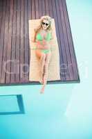 Beautiful woman in green bikini relaxing by pool side