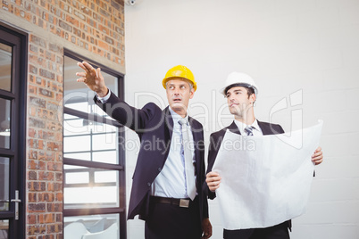 Male architect with colleague holding blueprint