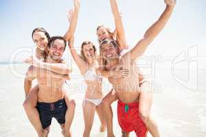 Men giving a piggy back to women on the beach