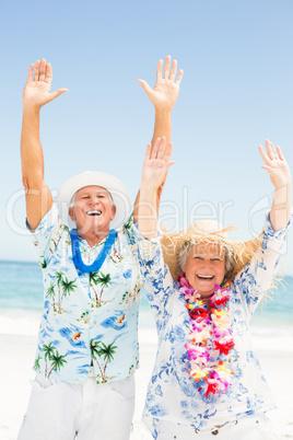 Senior couple with arms up on the beach
