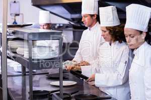 Team of chefs arranging plates on the order station