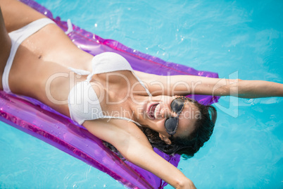 Cheerful young woman swimming with inflatable raft
