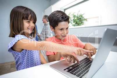 Happy boy and girl using laptop