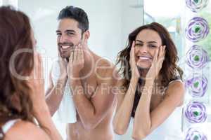 Young couple cleaning face in bathroom