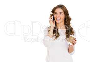 Happy young woman talking on mobile phone while having coffee