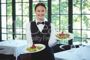 Smiling waitress holding plates