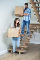 Cheerful couple holding cardboard boxes on steps