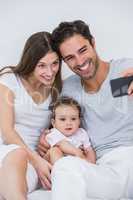 Couple clicking selfie with baby on bed