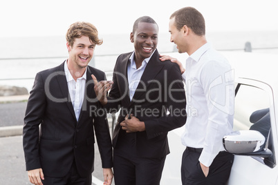 Well dressed people posing next to a limousine